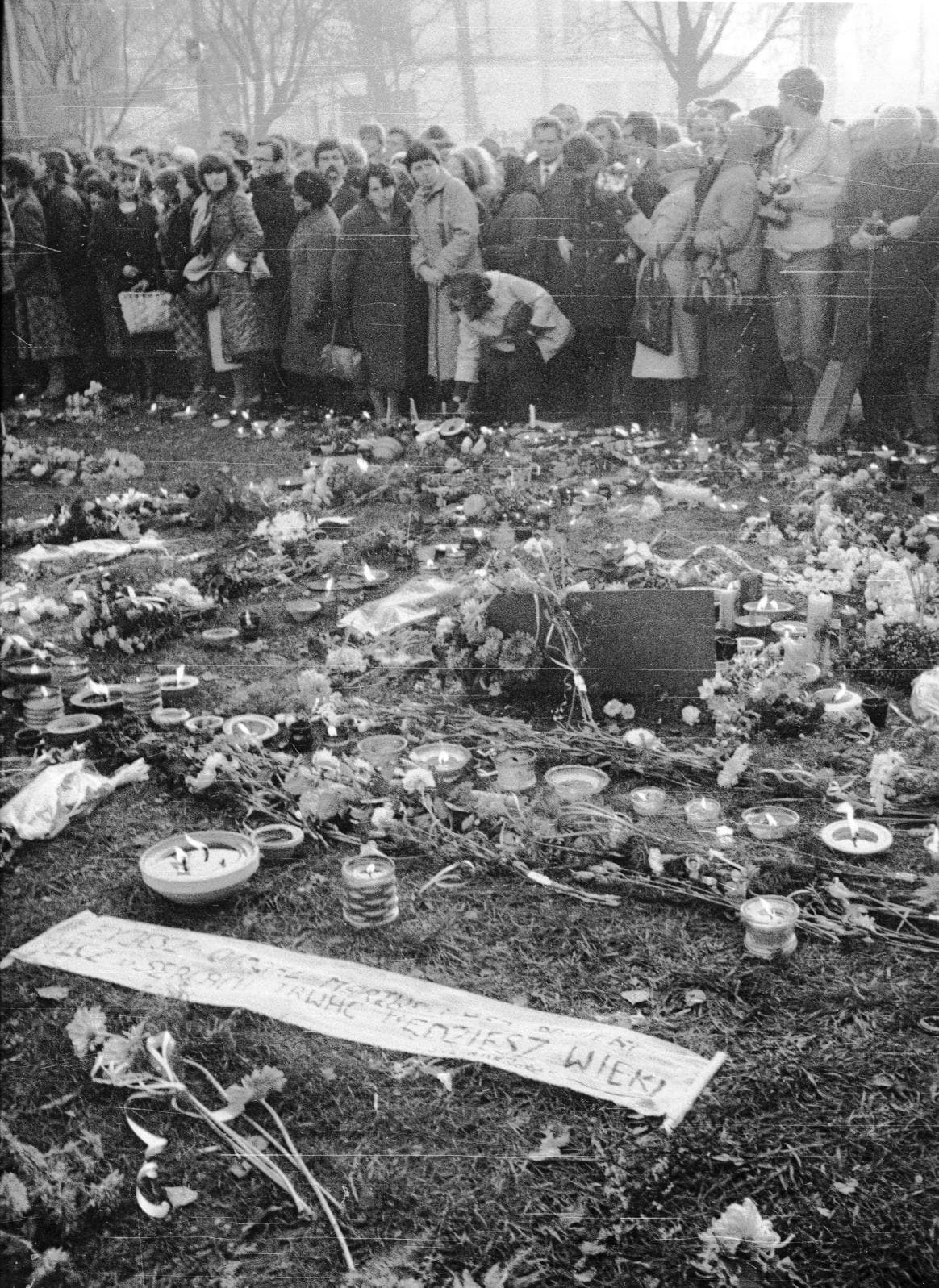Верующие молятся перед цветами и свечами на могиле Ежи Попелушко в 1984 году