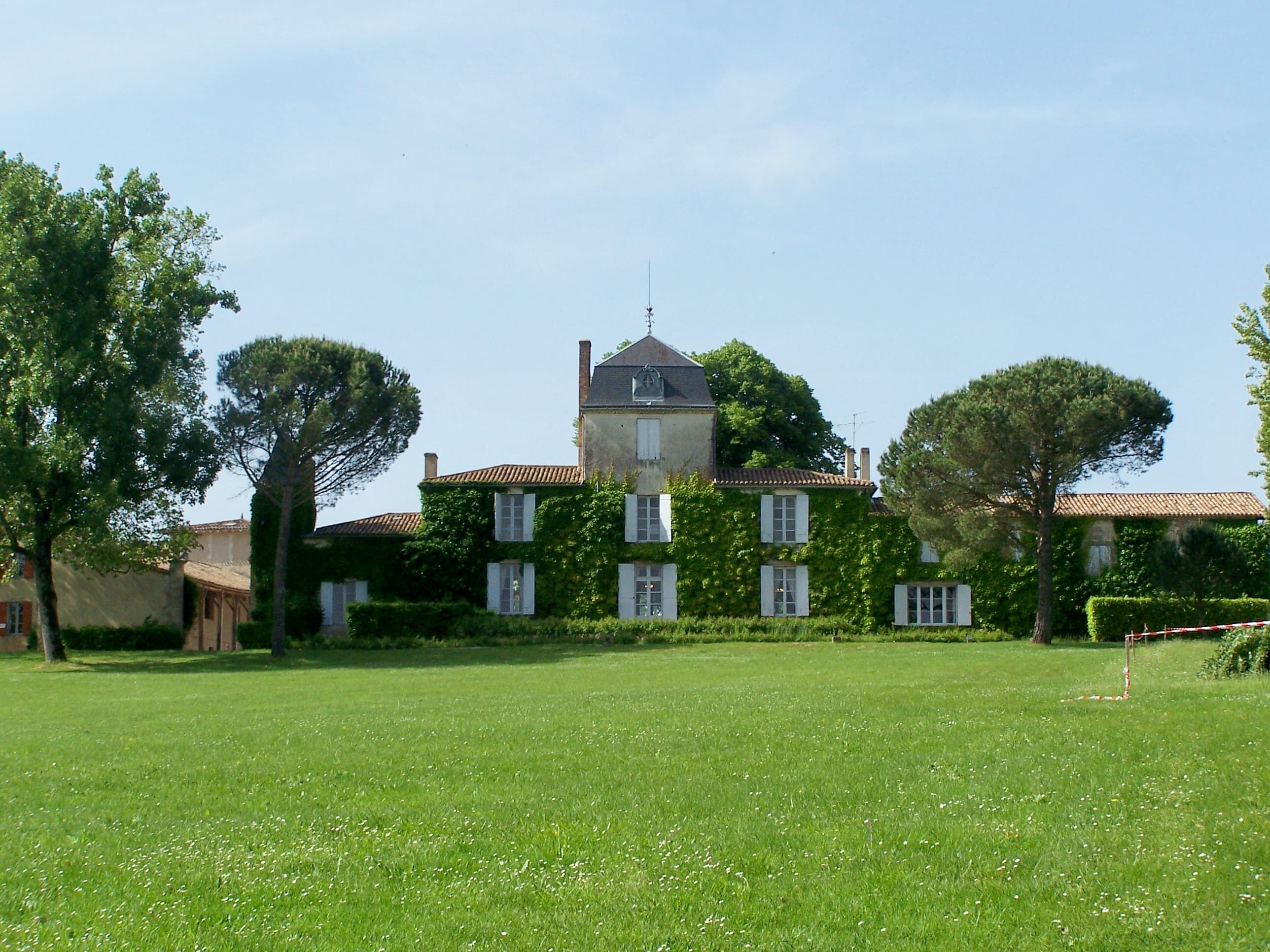 Facade of the Malagar estate surrounded by pine trees, in Gironde