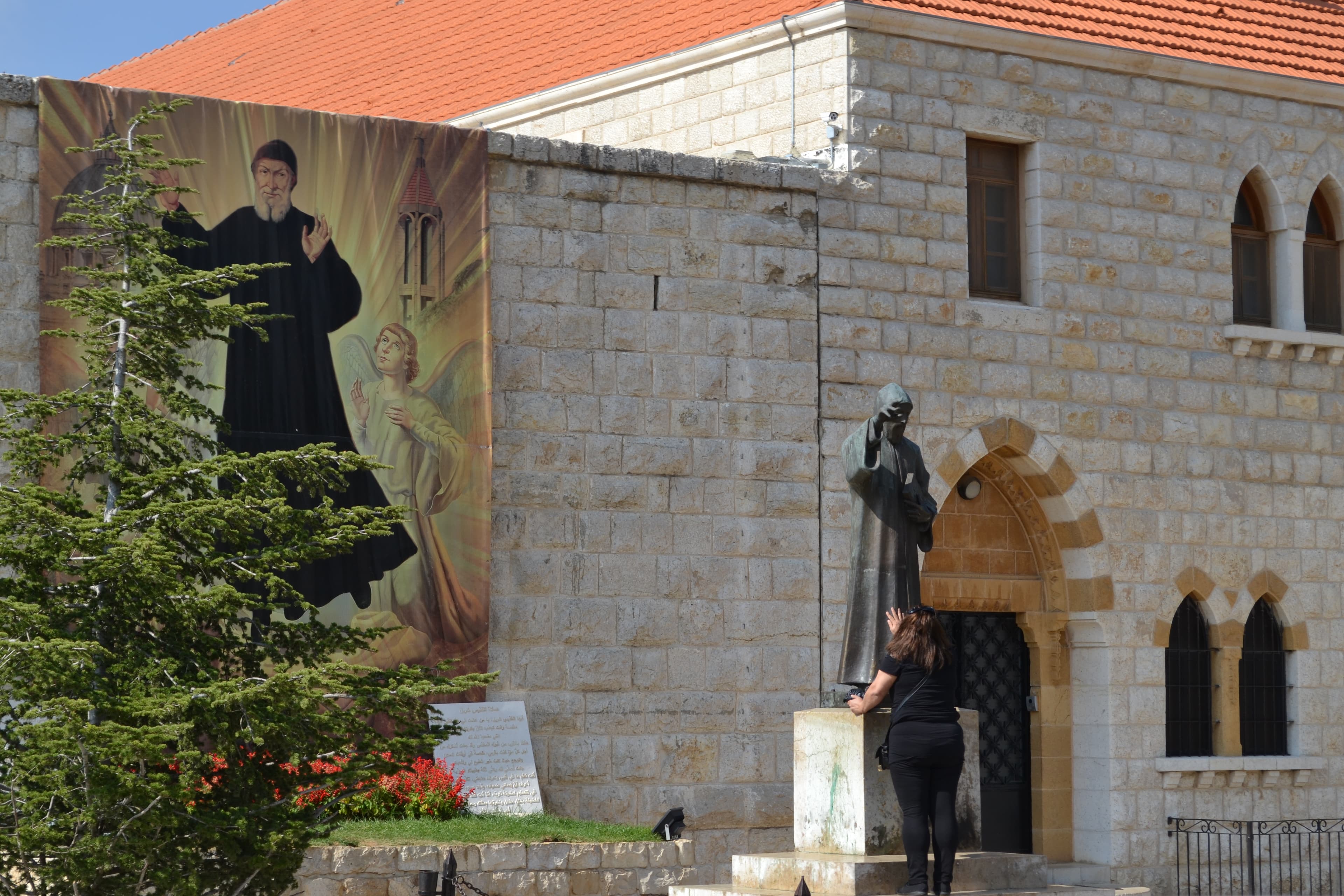 Une fidèle devant la statue de saint Charbel au sanctuaire d’Annaya