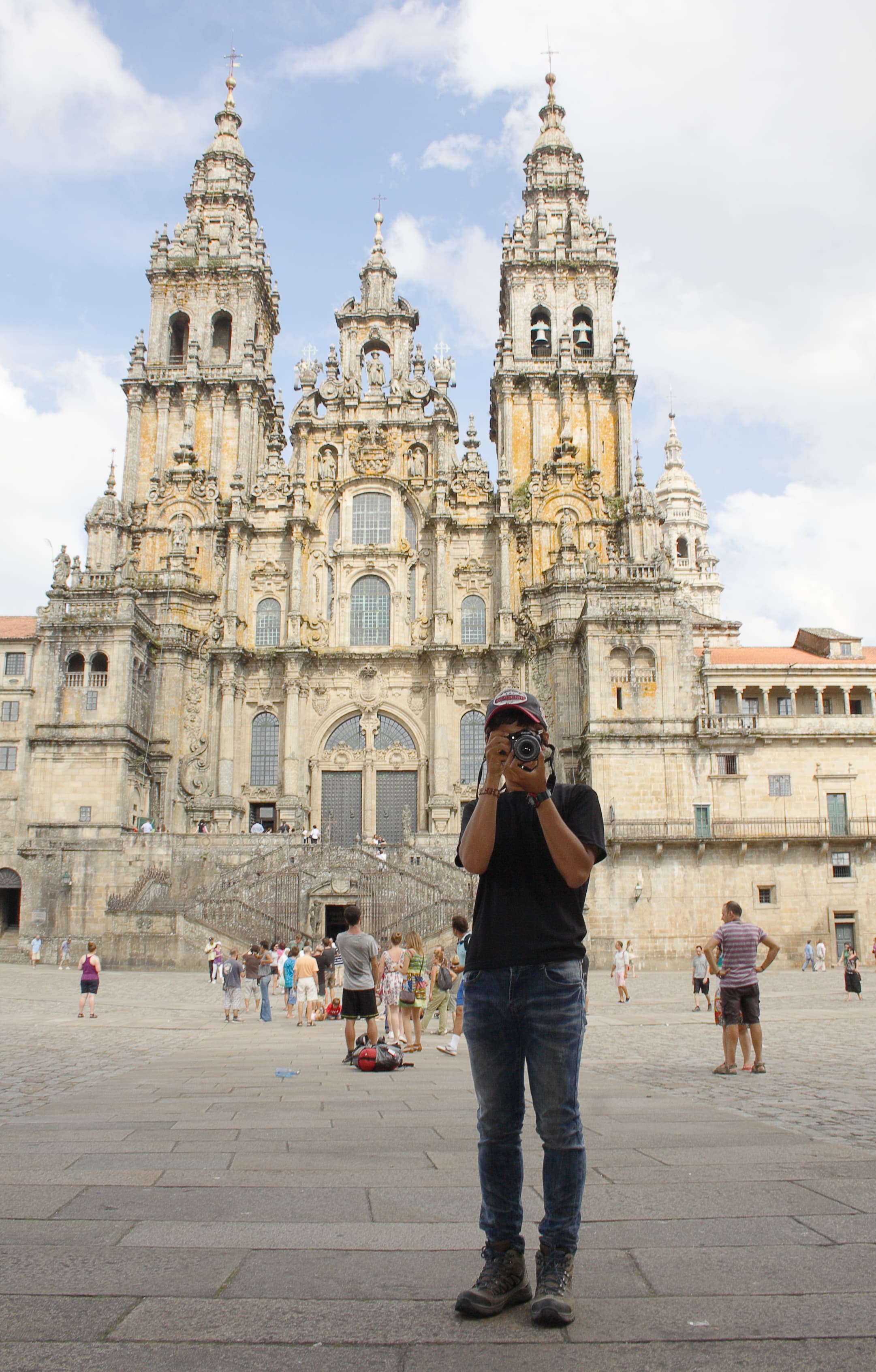Peregrinos com mochilas na praça do Obradoiro, diante da fachada da catedral de Santiago