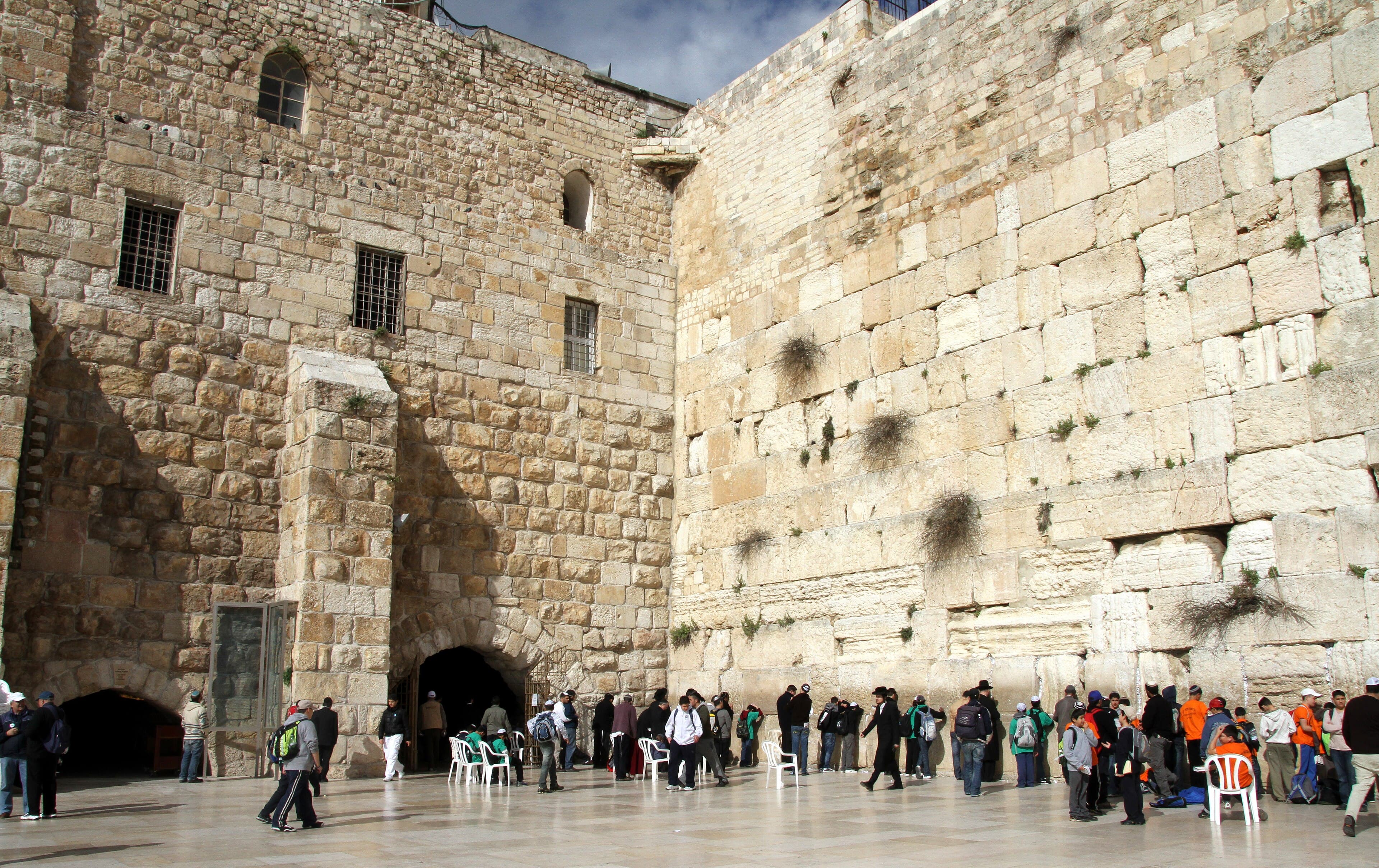 O Muro das Lamentações em Jerusalém, com fiéis a rezar na sua base