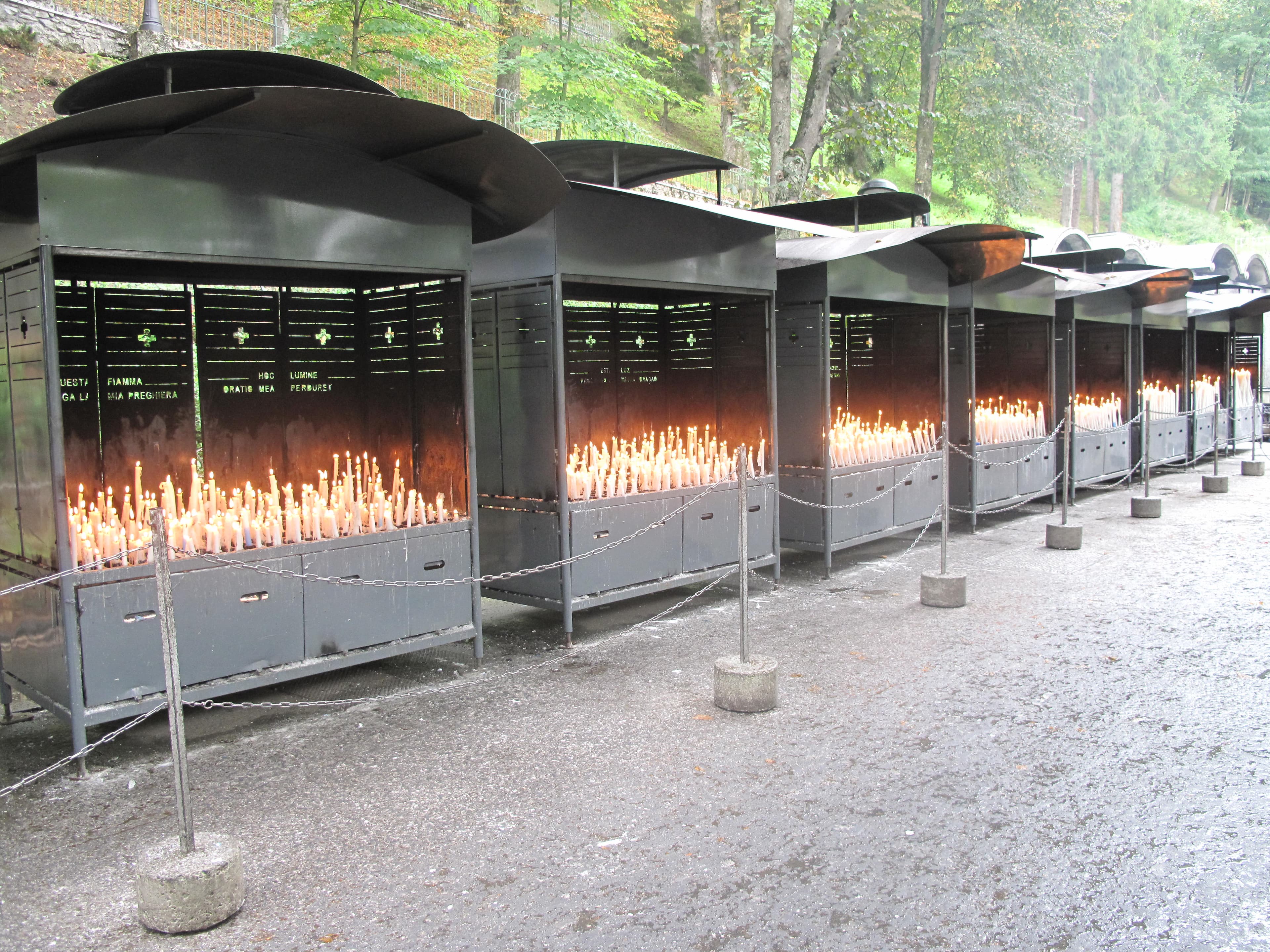 Fileiras de velas votivas acesas junto à gruta de Massabielle, em Lourdes