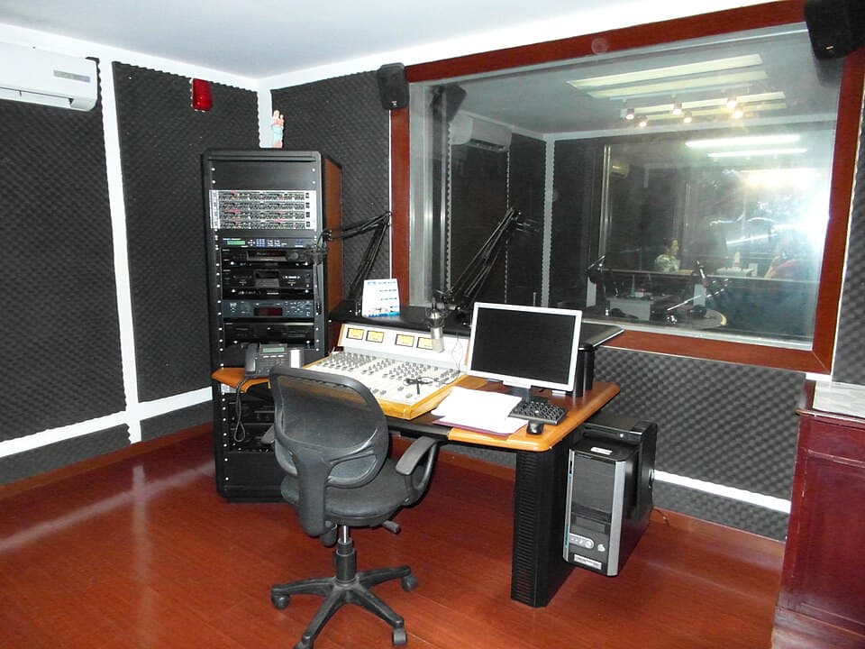 Régie d'un studio Radio Maria, console de mixage et cabine d'animation derrière la vitre