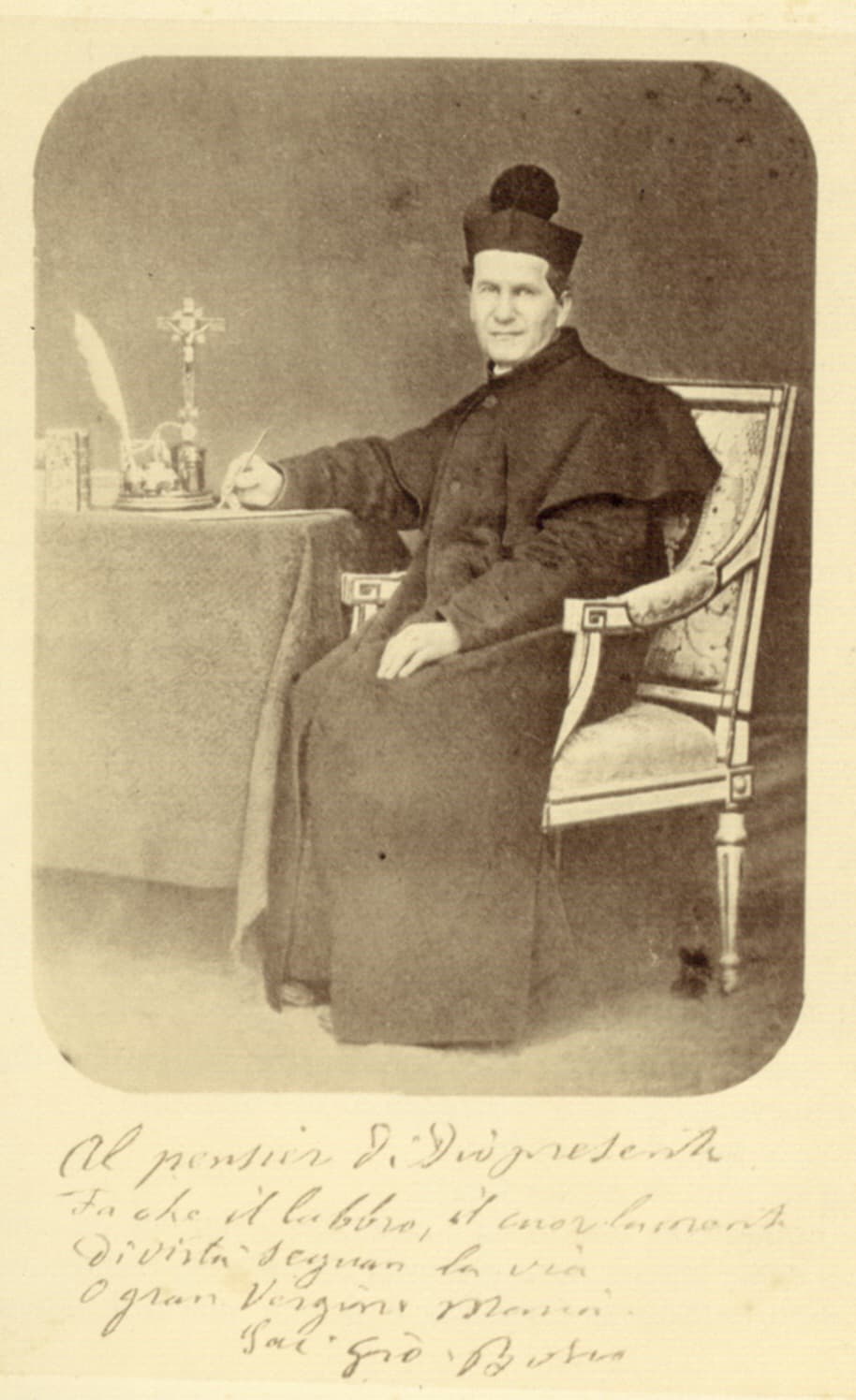 Jean Bosco assis à une table, écrivant, photographié à Turin entre 1865 et 1868.