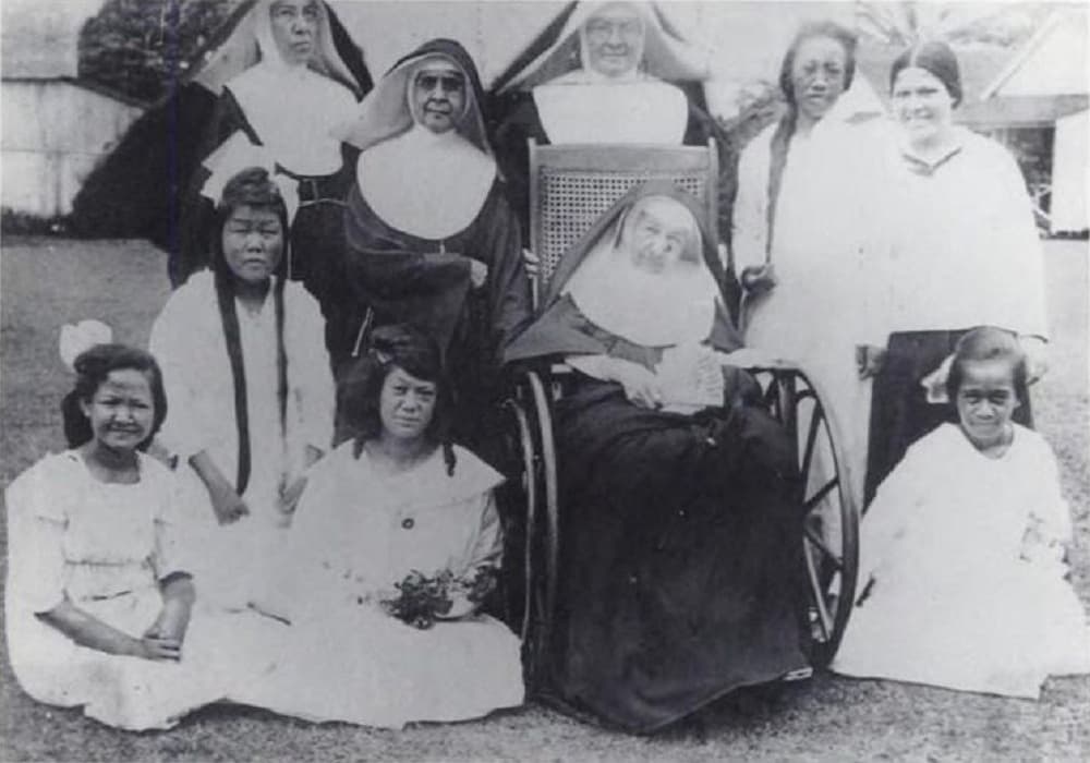 Mutter Marianne im Rollstuhl mit Mitschwestern, Patientinnen und Mädchen des Bishop-Heims in Kalaupapa, kurz vor ihrem Tod 1918