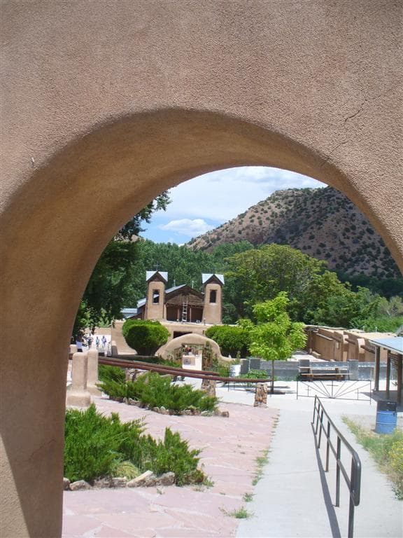 El Santuario visto a través del antiguo portal en arco, con la ladera de Chimayó detrás.
