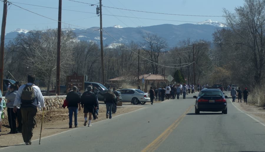 Peregrinos caminando hacia el Santuario, con el pico Truchas al fondo.