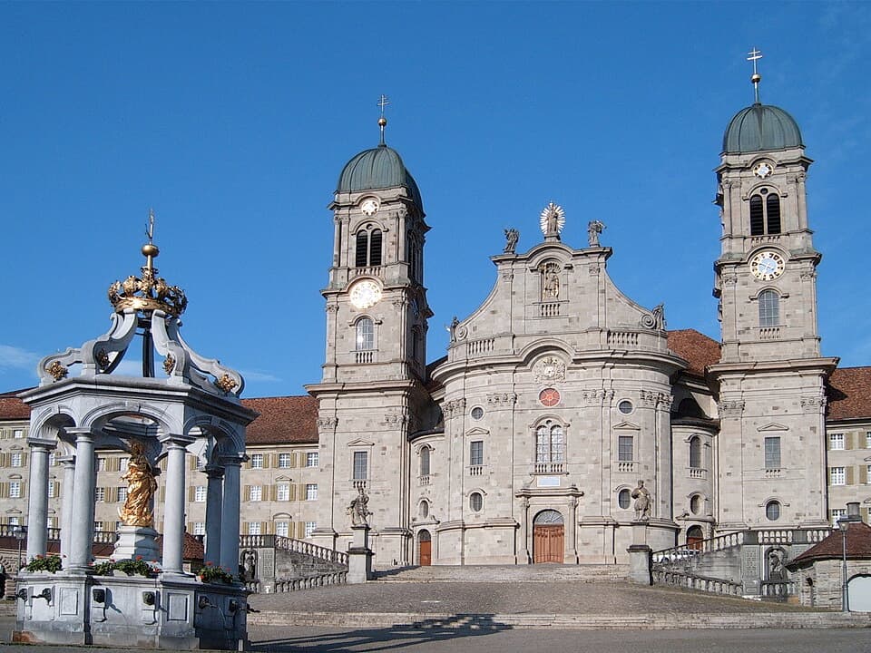 Doppeltürmige Fassade der Abtei Einsiedeln mit dem Marienbrunnen im Vordergrund
